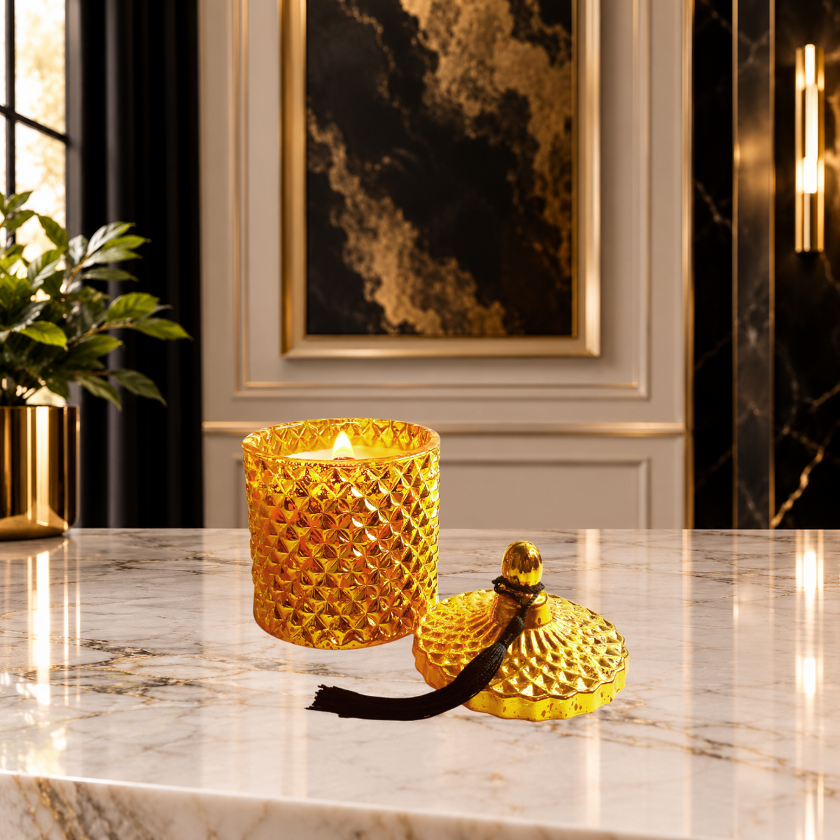 A textured gold glass candle jar, the LéShay Candles Blessed Home Luxury Diamond Jar Candle with a lit wood wick flame sits on a polished marble surface next to its matching gold lid, which has a black tassel. The background features elegant interior decor, including a gold-framed artwork and a black curtain.